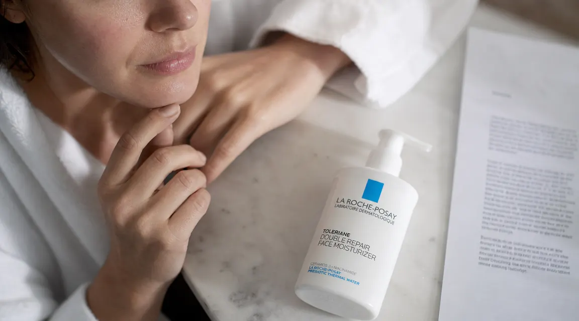 La Roche-Posay Toleriane Double Repair pump bottle lying on its side next to a printed ingredient list on white paper